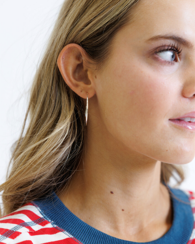 Close-up of a woman wearing hoop earrings on a white background