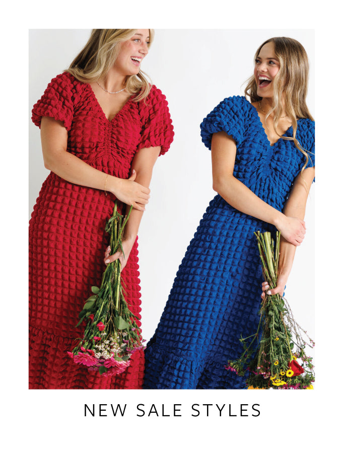 Two women wearing red and blue textured dresses holding flowers with 'NEW SALE STYLES' text.