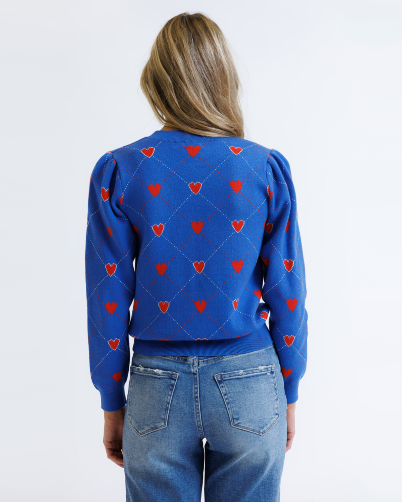 Woman wearing a blue sweater with red heart patterns on a white background