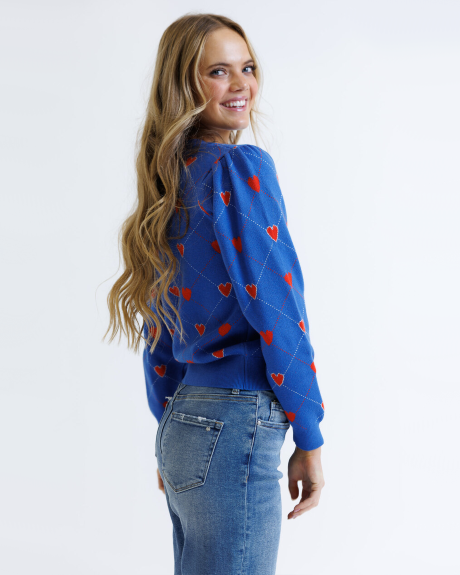 Woman wearing a blue sweater with red heart patterns on a white background