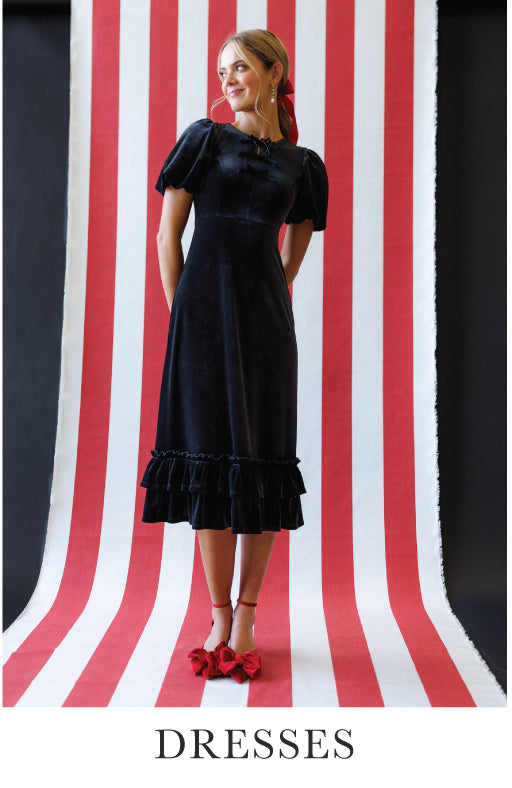 Woman wearing a black dress with ruffled details on a red and white striped background. Bottom text says "Dresses"
