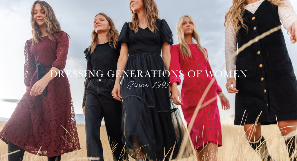 Five women in various outfits with text 'Dressing Generations of Women Since 1991' on a blurred outdoor background.