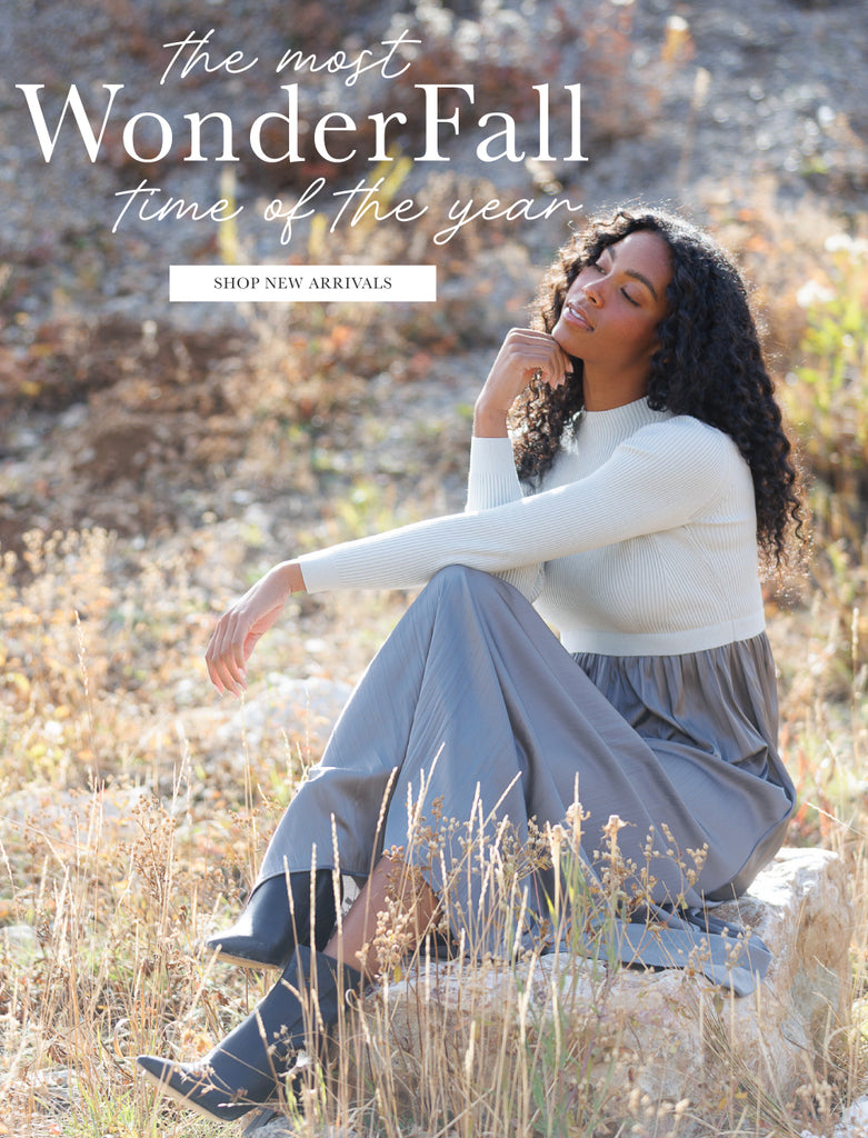 Woman sitting in a field with promotional text overlay says "The Most WonderFall Time of the Year" and has a button that says "Shop New Arrivals"