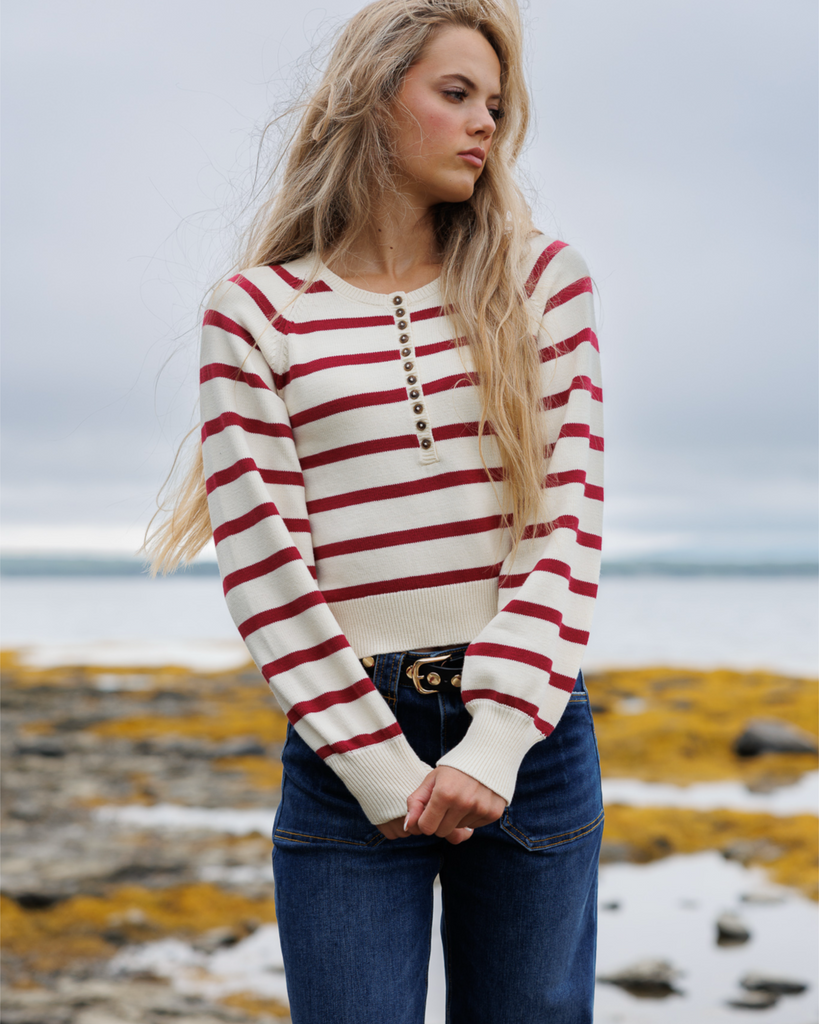 Woman wearing a red and white striped sweater standing outside.