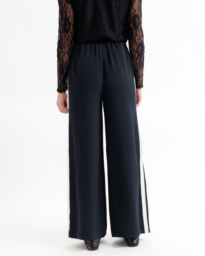 Black wide-leg pants worn with a black top on a white background