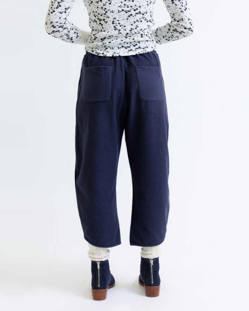 Person wearing navy blue pants and a patterned top on a white background