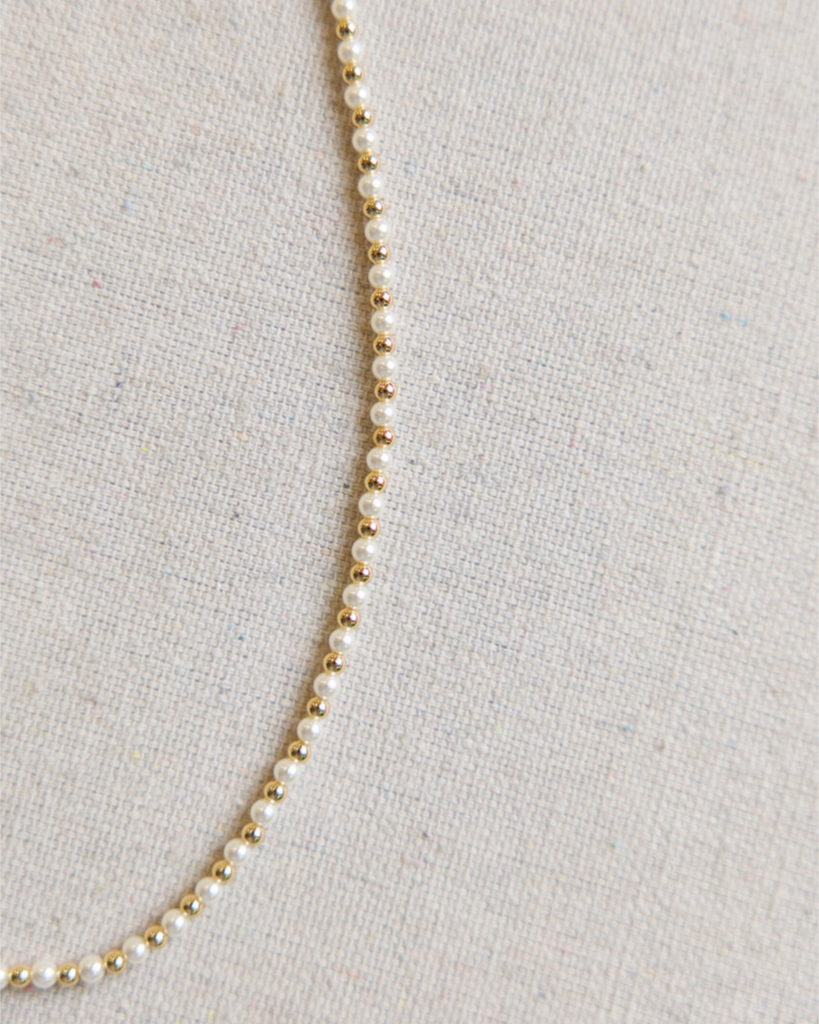 Close up image of a beaded necklace on a beige fabric background