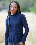 Woman wearing blue long sleeve top with black cheetah print outdoors.