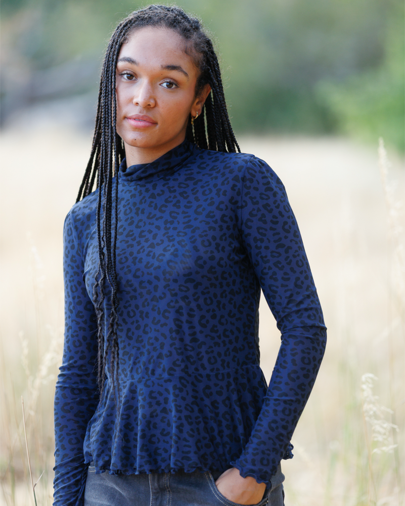 Woman wearing blue long sleeve top with black cheetah print outdoors.
