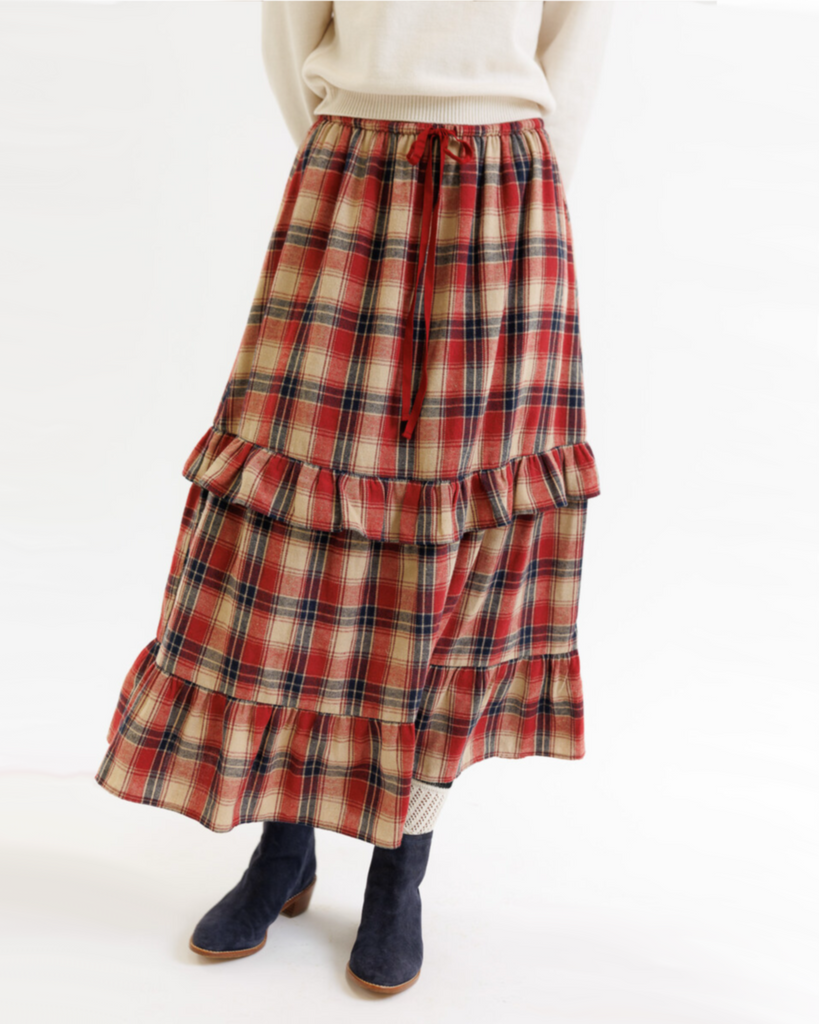Plaid skirt with ruffled layers worn by a woman on a white background