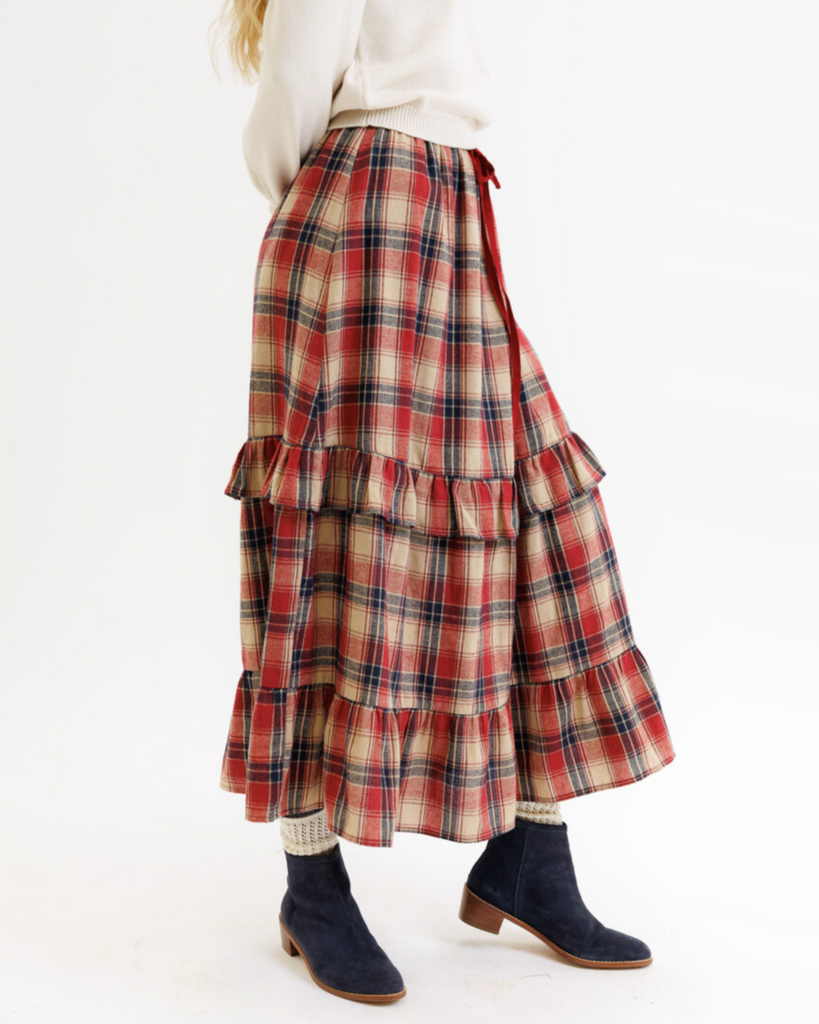 Plaid skirt with ruffled layers worn by a woman on a white background