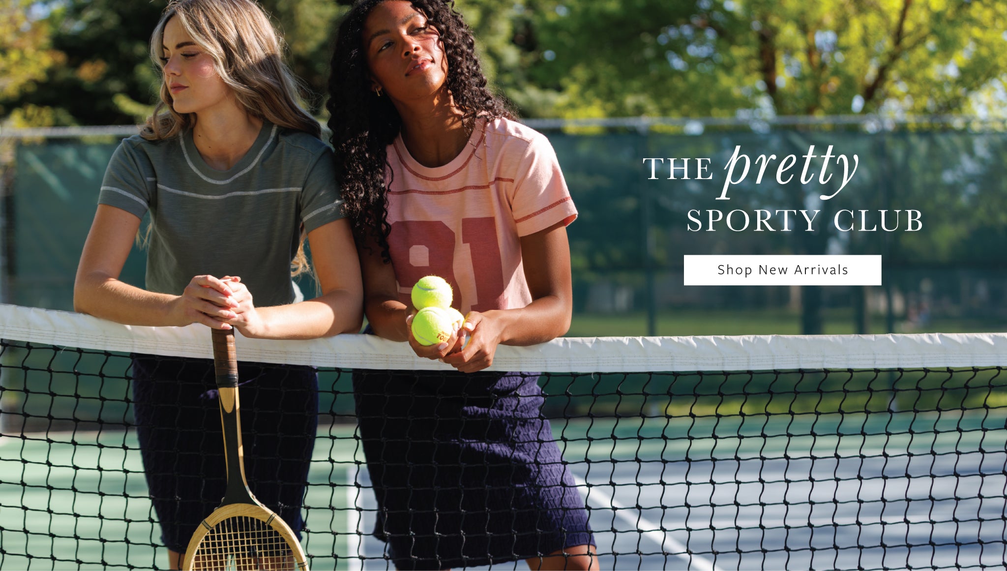 Two women on a tennis court behind a net, one holding a racket and the other holding two tennis balls. Text overlay reads 'THE pretty SPORTY CLUB' with 'Shop New Arrivals'.