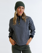 Woman wearing a black and white checkered pullover with a green beanie on a white background