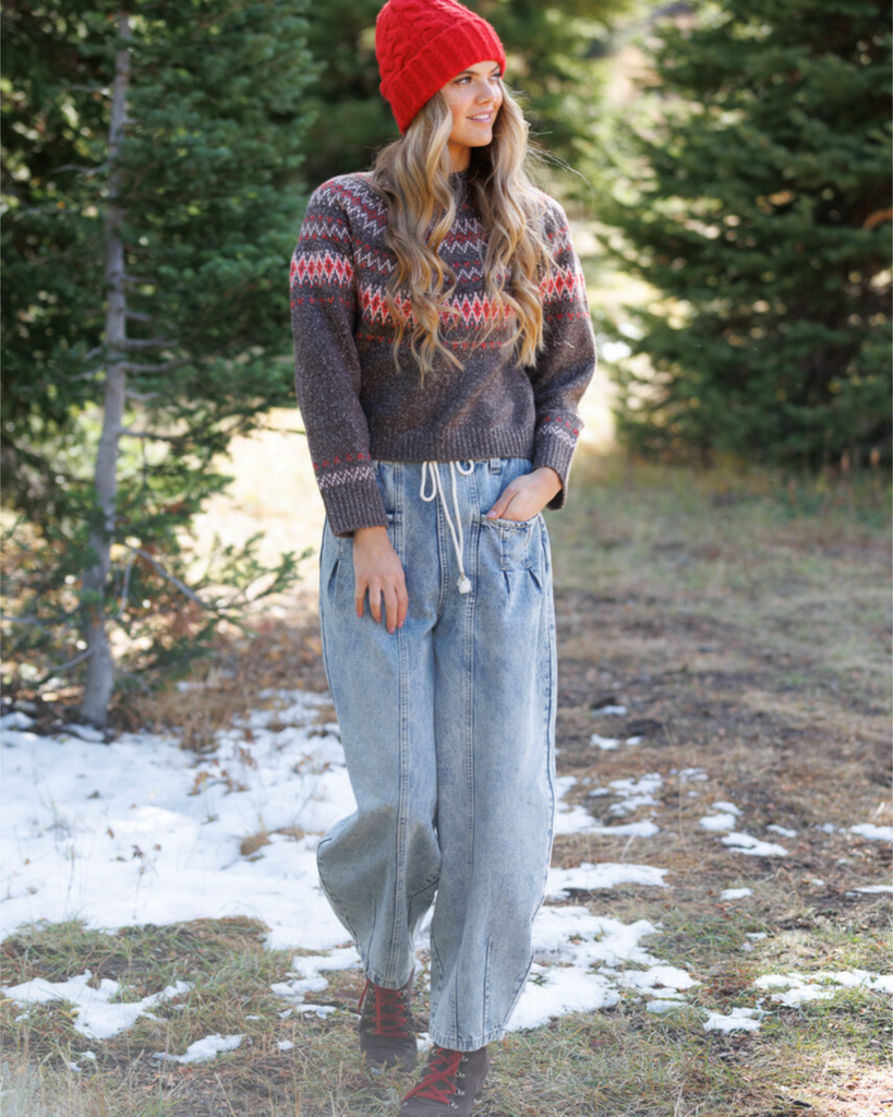 Woman wearing a printed sweater and lightwash jeans in the outdoors