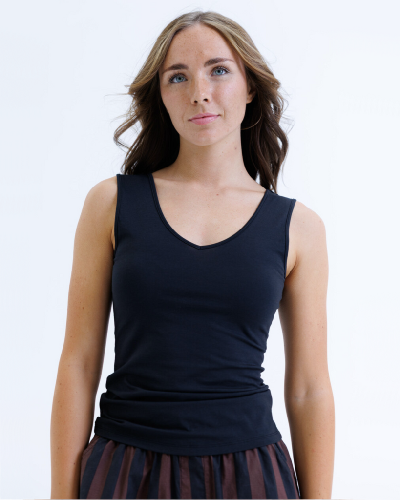 Woman wearing a black layering tank top against a white background