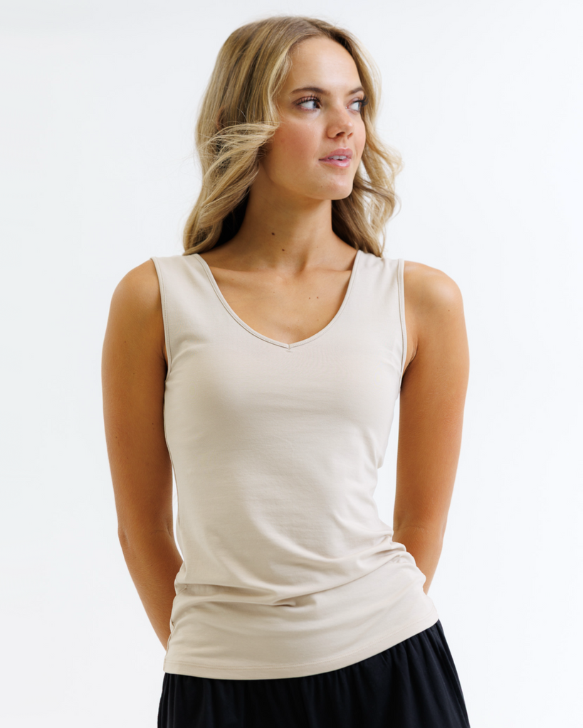 Woman wearing a beige tank top on a white background