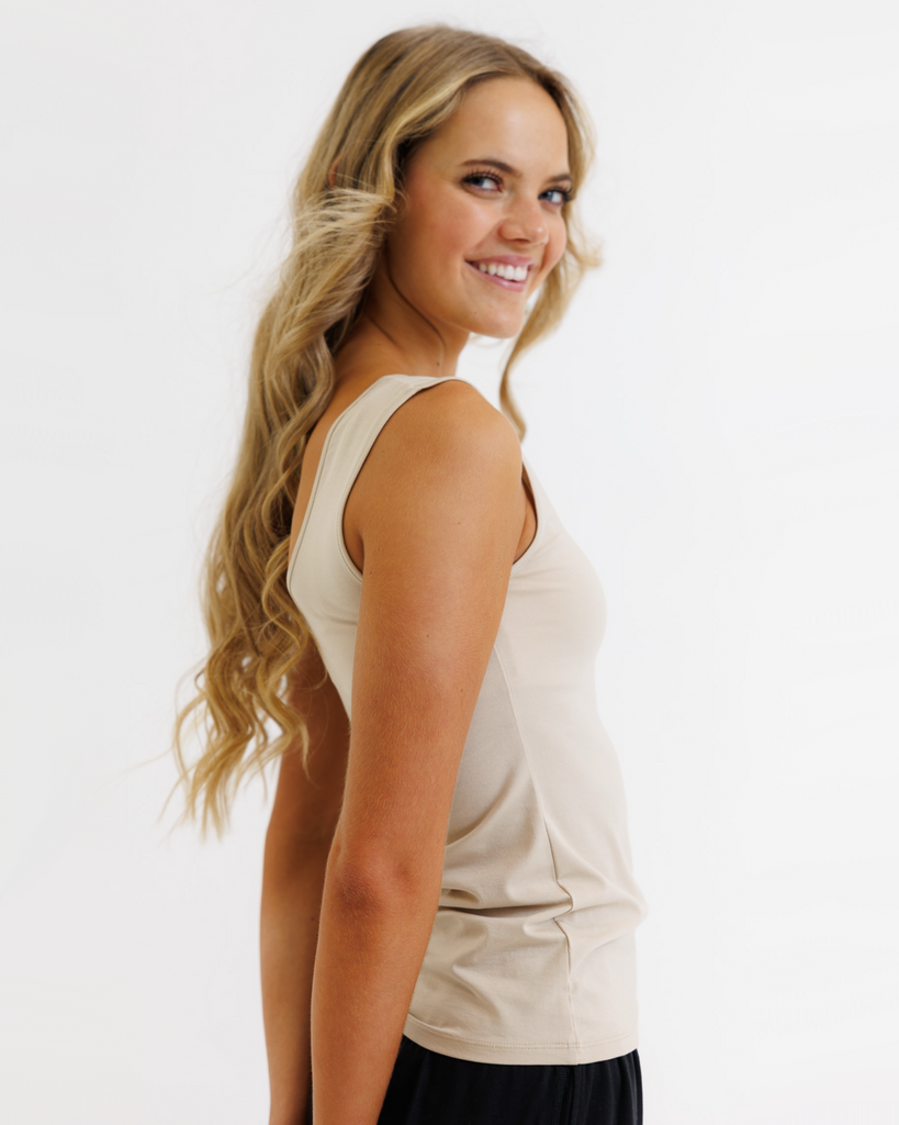 Woman wearing a beige sleeveless top on a white background