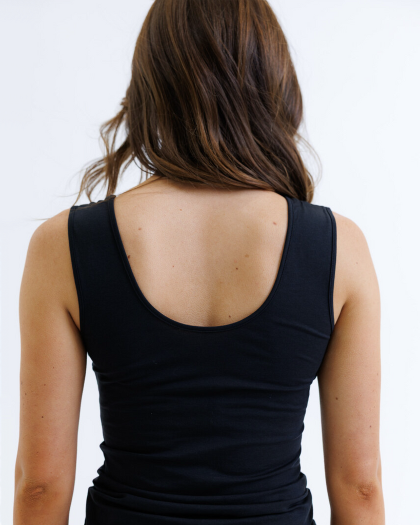 Woman wearing a black layering tank top against a white background