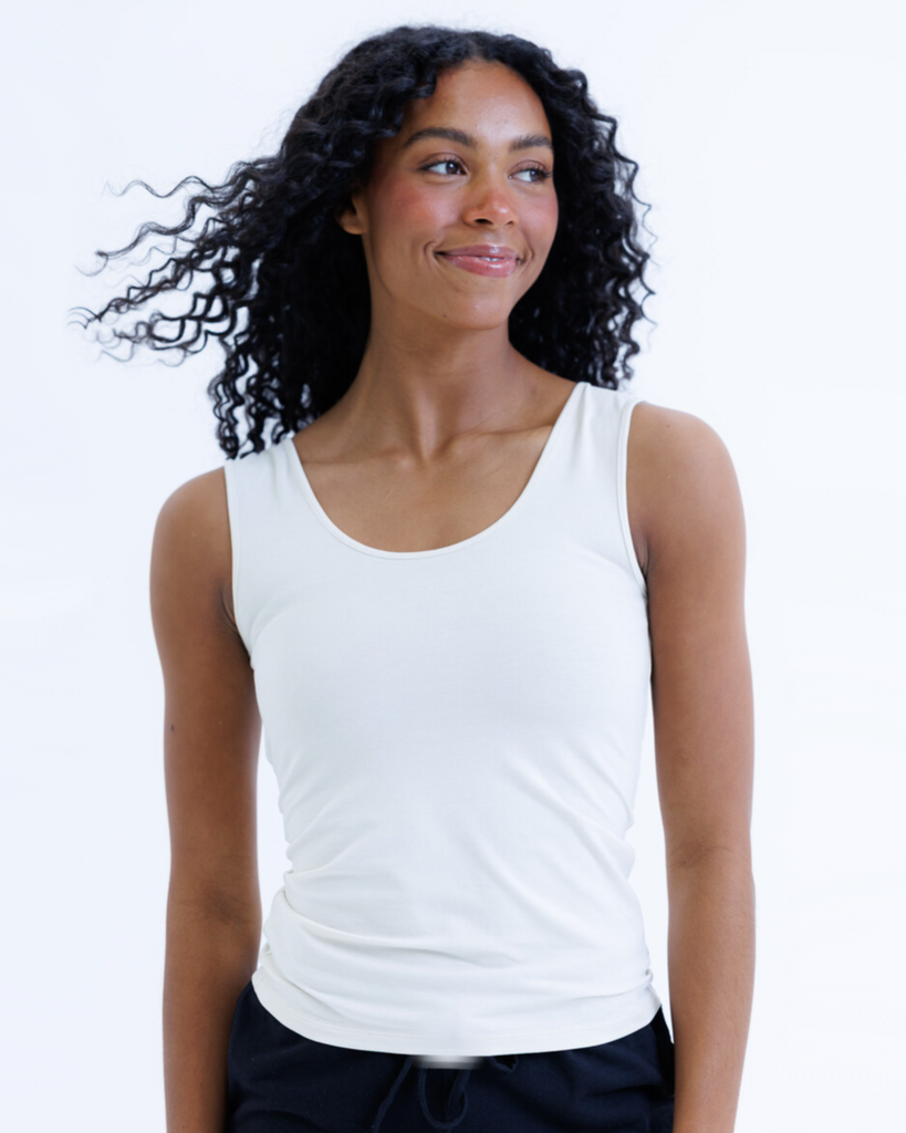 Woman wearing a cream colored layering tank top against a white background