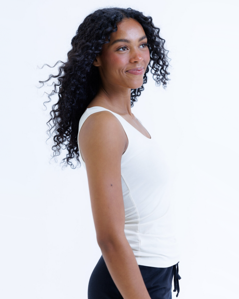 Woman wearing a cream colored layering tank top against a white background