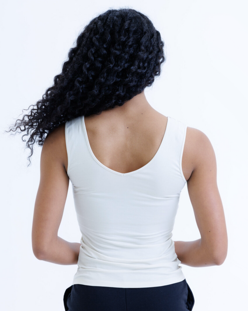 Woman wearing a cream colored layering tank top against a white background