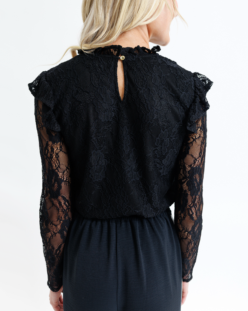 Black lace top worn by a woman on a white background