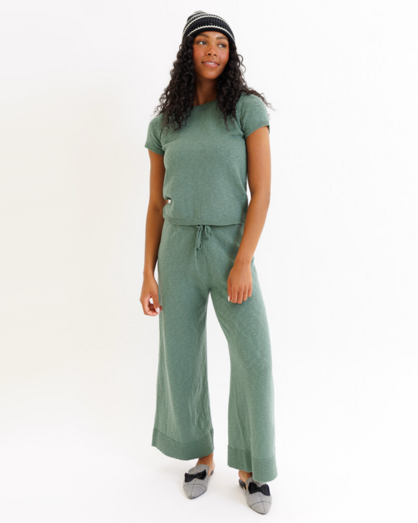 Woman wearing a green matching set with wide-leg pants on a white background