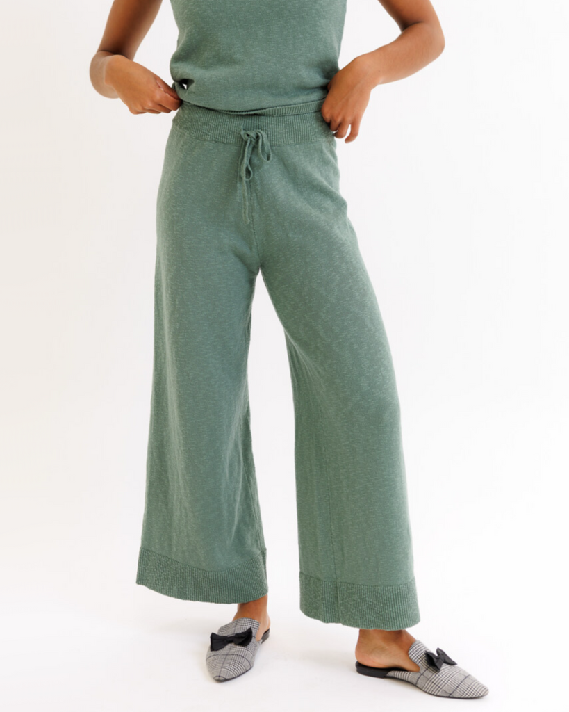 Woman wearing green wide-leg lounge pants on a white background