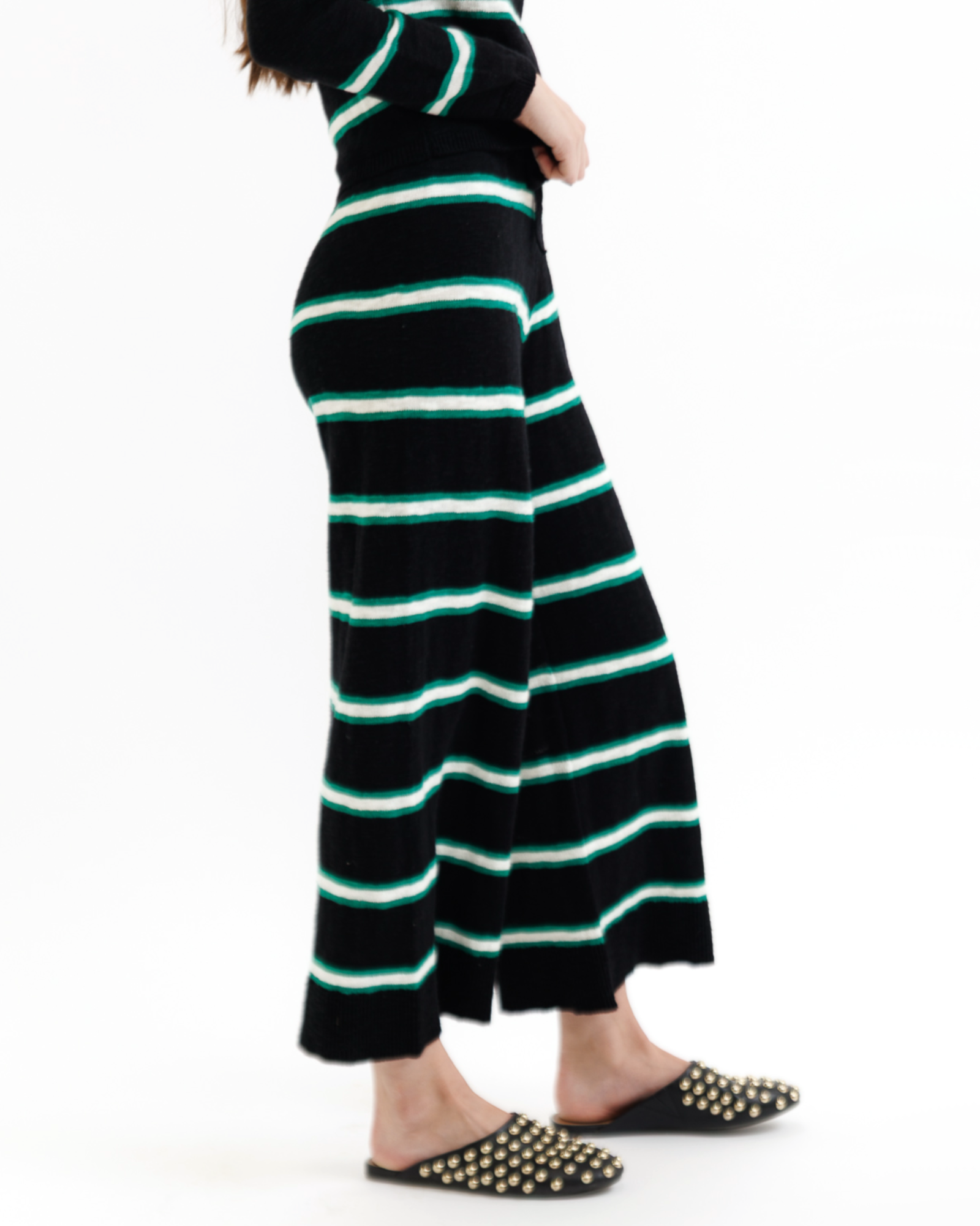 Woman wearing a black striped pants with green accents on a white background
