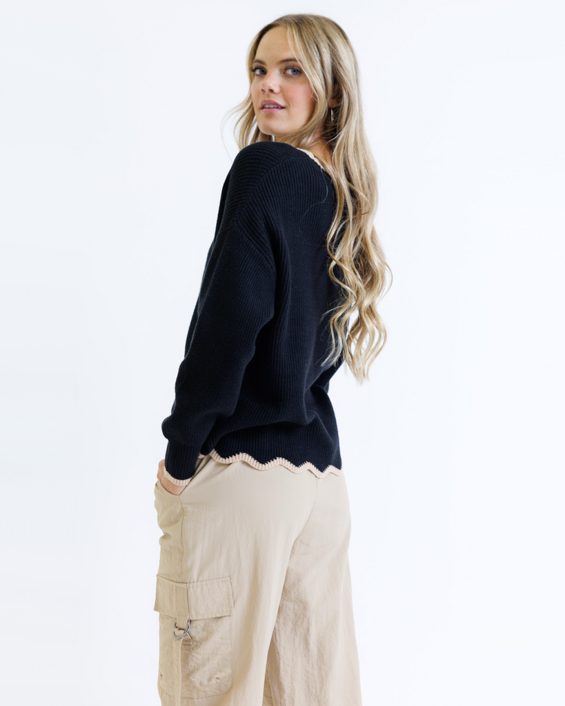 Woman wearing a black sweater and beige pants on a white background