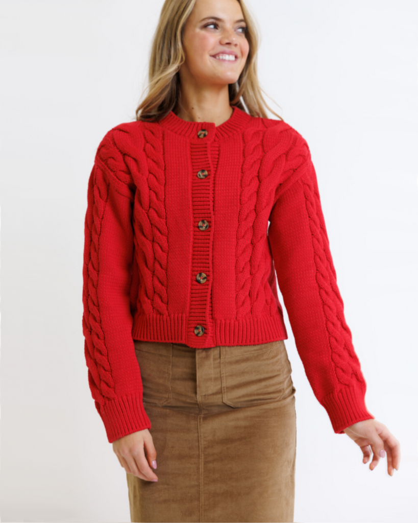 Woman wearing a red cable knit sweater on a white background