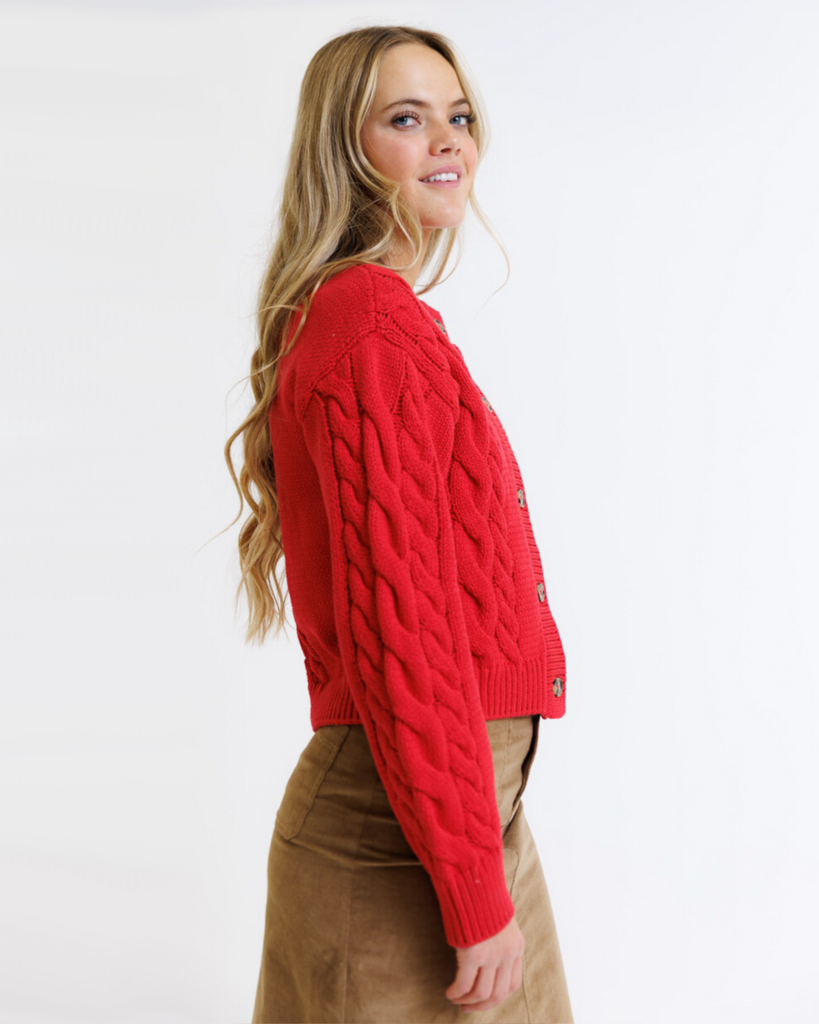 Woman wearing a red cable knit sweater on a white background