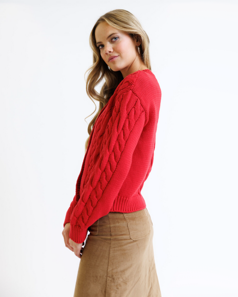 Woman wearing a red cable knit sweater on a white background