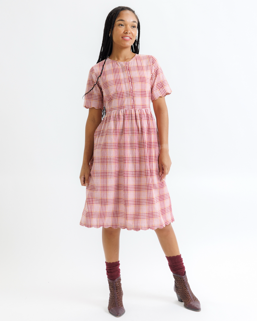 Woman wearing a pink plaid dress on a white background