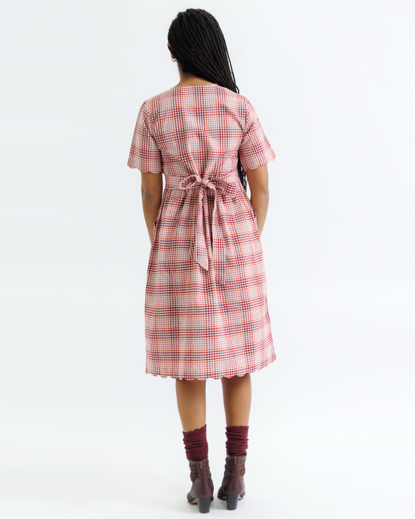 Woman wearing a pink plaid dress on a white background
