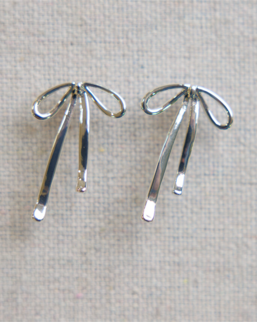 Silver bow-shaped earrings on a light gray background
