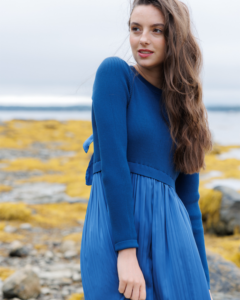 Woman wearing a blue long sleeve dress outside.