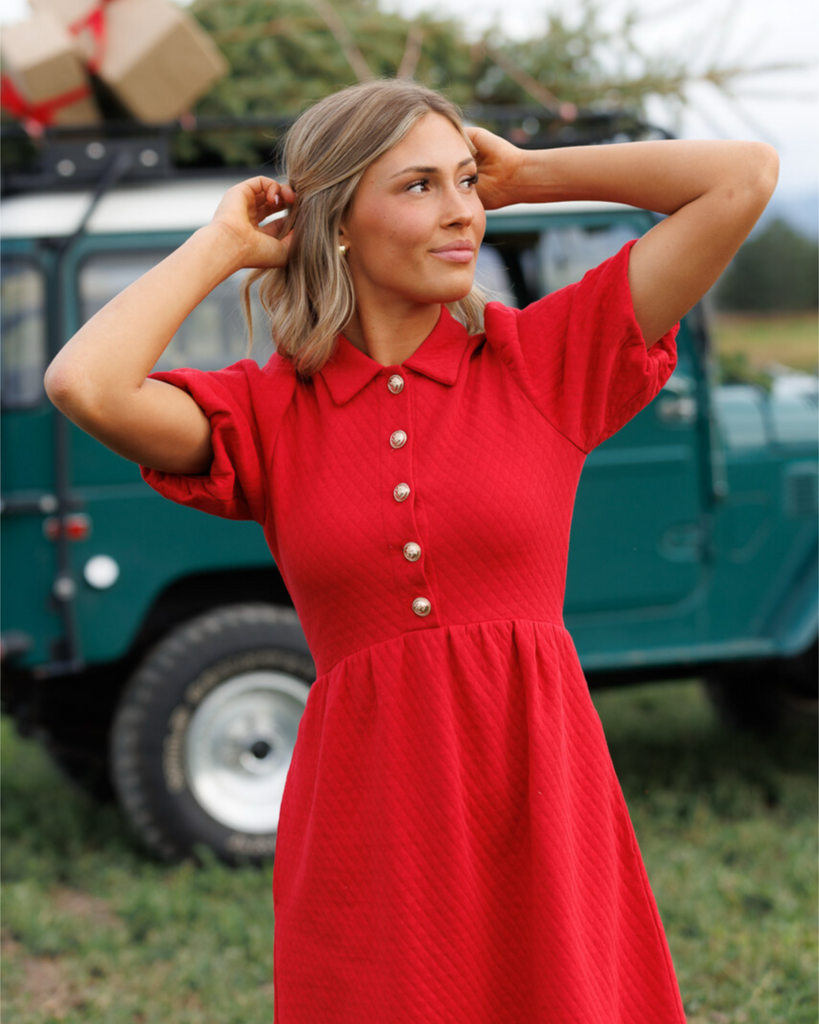 Woman in a red dress standing in front of a vintage vehicle