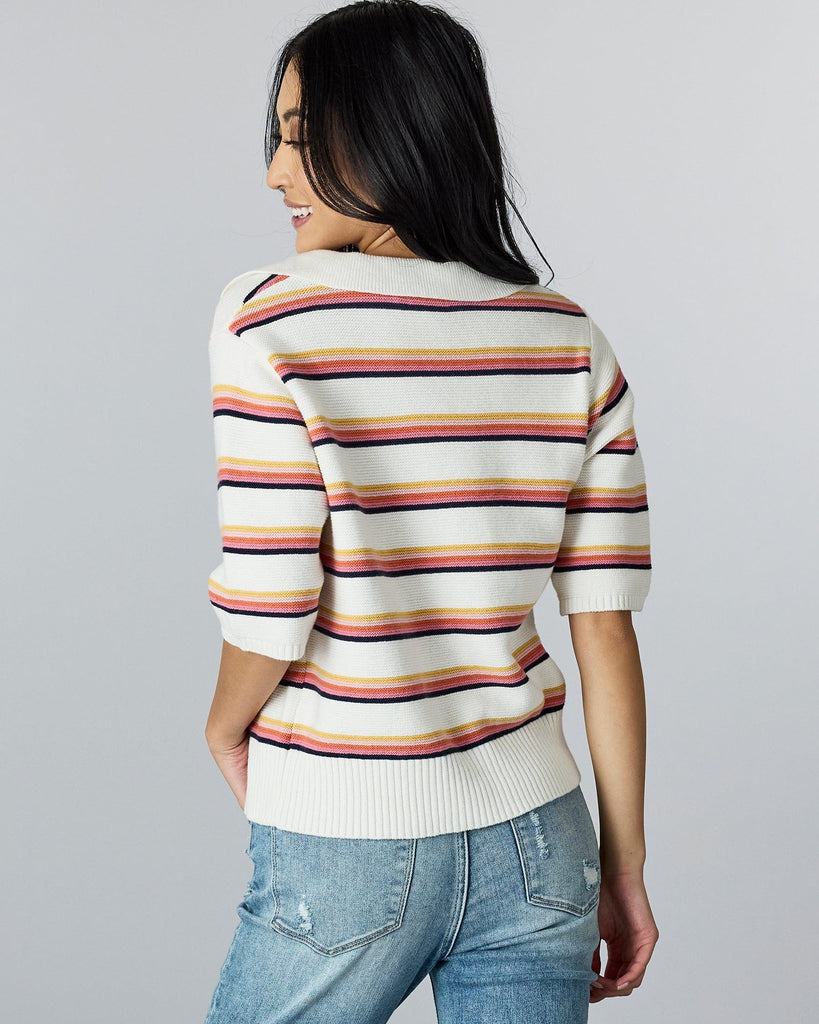 Woman in a half-sleeved, rainbow striped sweater with v-neck and collar.