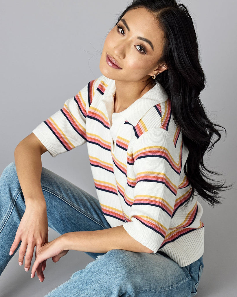 Woman in a half-sleeved, rainbow striped sweater with v-neck and collar.