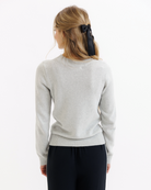 Woman wearing a gray sweater and black pants on a white background