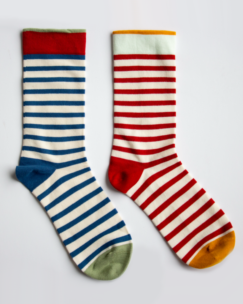 Two pairs of striped socks, one with blue and white stripes and the other with red and white stripes, on a light gray background.