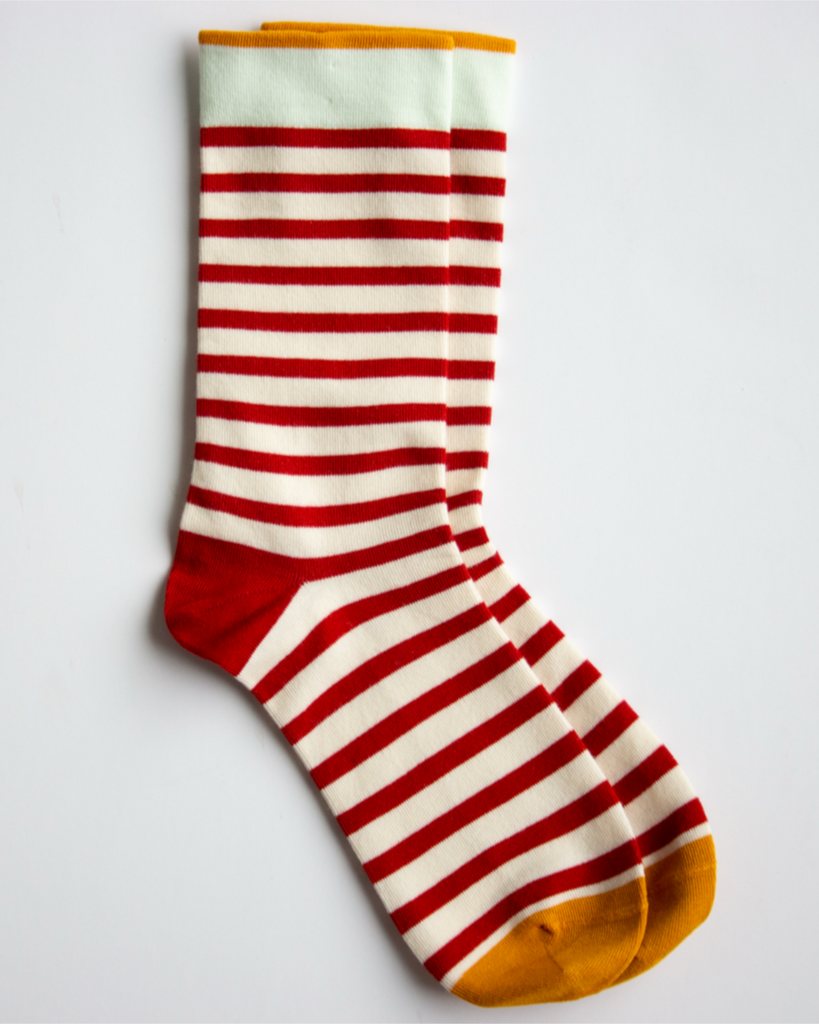 Red and white striped sock with yellow toes and cuffs on a light gray background