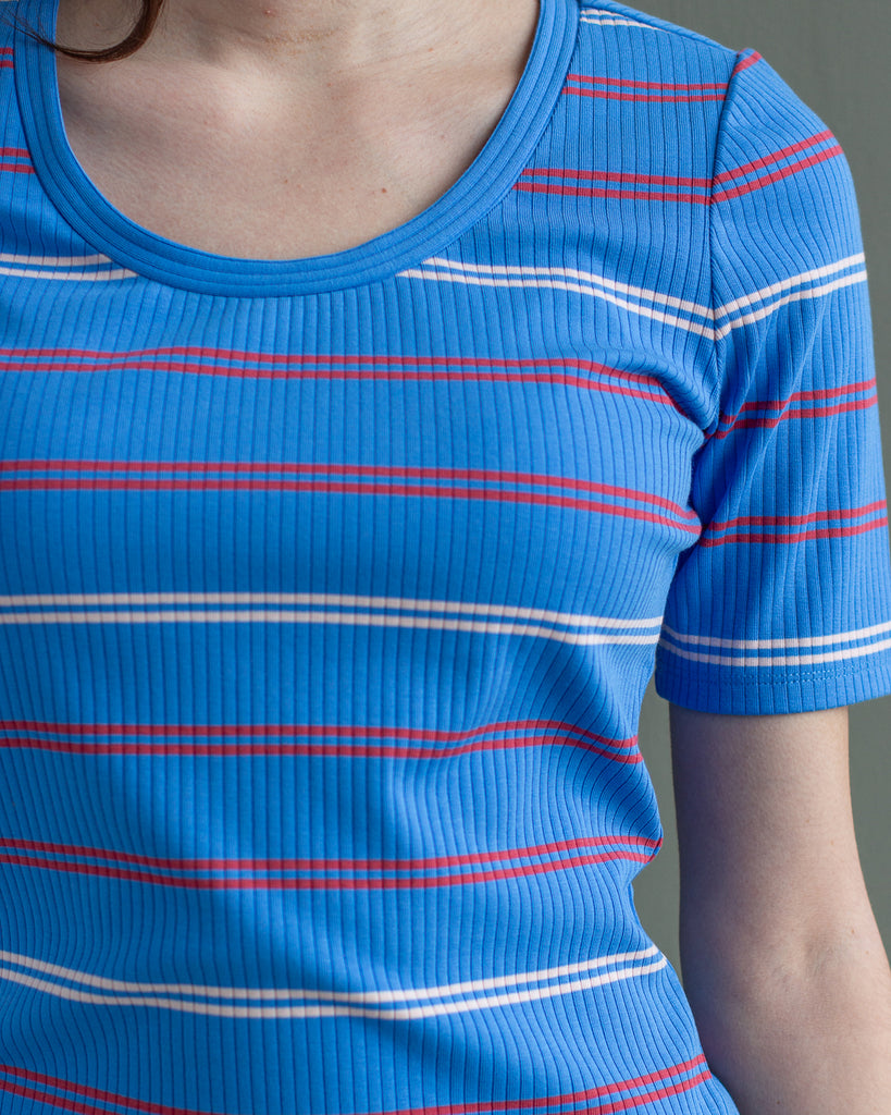 Model wearing a blue with white and red striped half sleeve scoop neck t-shirt