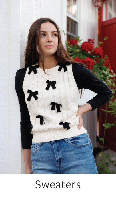 Woman wearing a sweater with black bow details in an outdoor setting