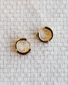 Gold hoop earrings on a textured white surface