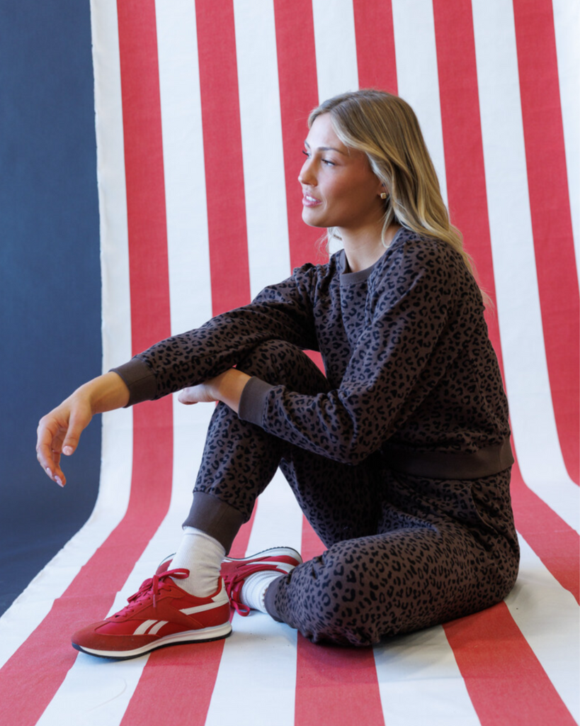 Woman wearing an animal print sweatshirt and sweatpants set on a striped background