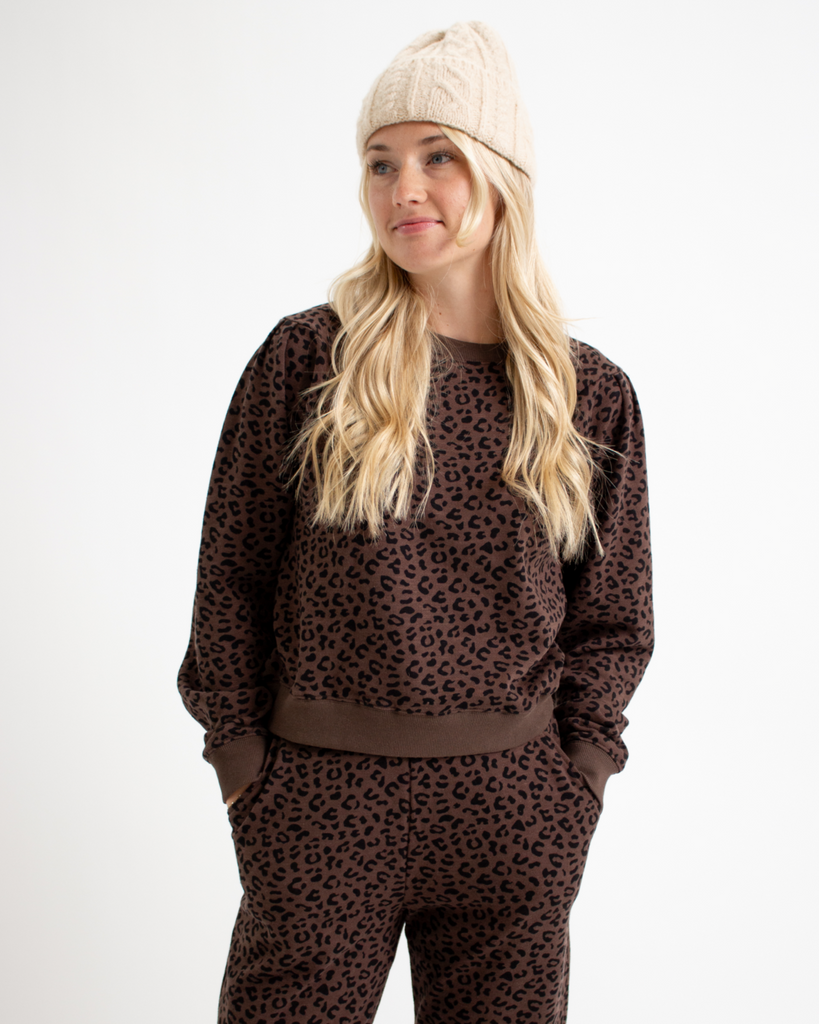 Woman wearing an animal print sweatshirt and sweatpants set on a white background