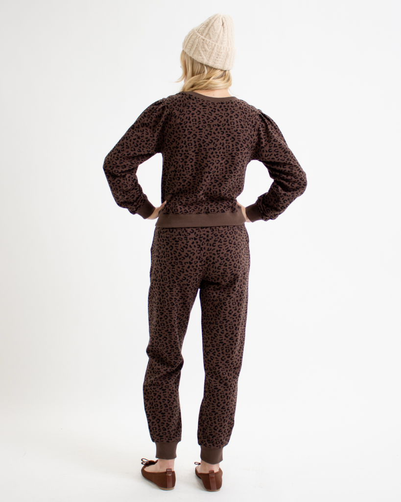 Woman wearing an animal print sweatshirt and sweatpants set on a white background