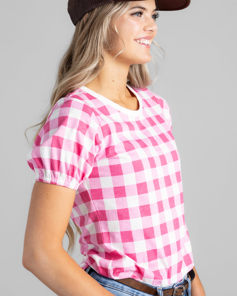 Model wearing a bright pink and white gingham print short sleeve t-shirt.